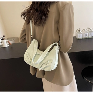 Detail of light green ruched leather handbag with side bows worn with a brown blazer