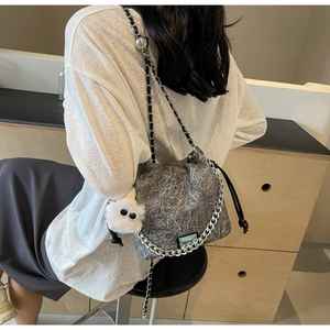 Detail of dark grey marble texture bag with silver chain and white plush charm