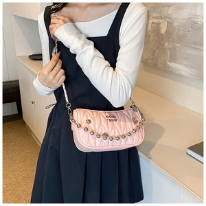 Detail of pink quilted leather crossbody bag with silver heart chain and wave stitching