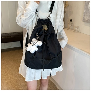 Detail eines minimalistischen schwarzen Nylon-Rucksacks mit Netzfach und Bärenanhänger
