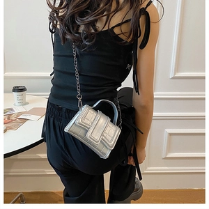 Silver crocodile pattern mini bag worn by a model with a metallic chain strap