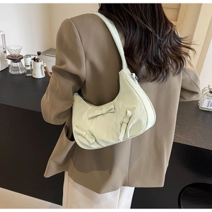 Side view of a mint green pleated crescent bag with 3D bows worn by a model