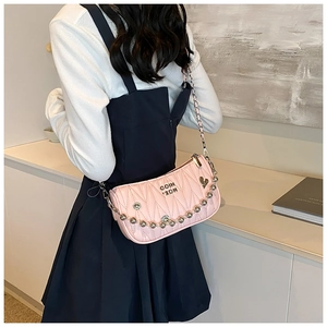 Pink crossbody bag with silver chain and heart pendant shown on model's shoulder