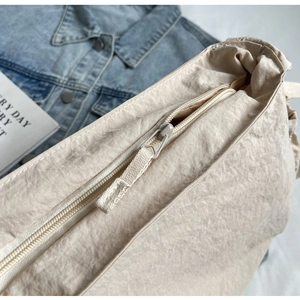 Detail view of the beige nylon hobo bag featuring a smooth zipper closure and texture