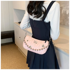 Pink quilted shoulder bag detail featuring silver ball chain and heart rhinestone charm