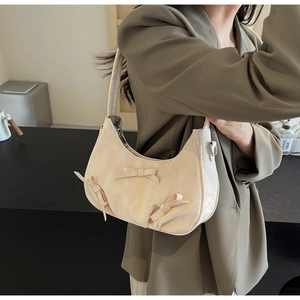Detail of three bows on a cream crescent shoulder bag with pleated faux leather texture