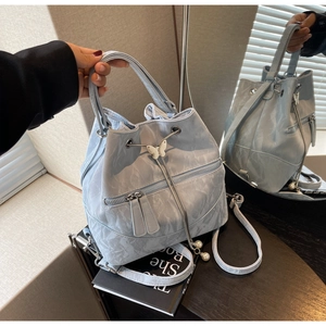 Detail of light blue bucket bag with marble texture, butterfly clasp, and pearl charms
