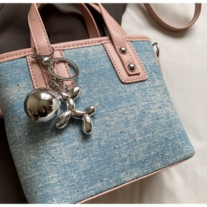 Close-up of blue denim bucket bag with silver studs and pink leather handle details