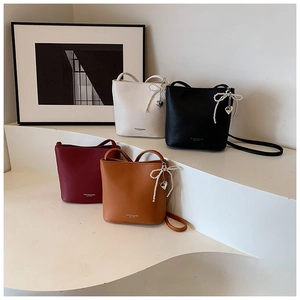 Detail of multi-color litchi leather bucket bags with pearl bow and heart charms
