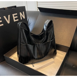 Gros plan sur un grand sac cabas noir brillant plissé dans un coffret cadeau de luxe