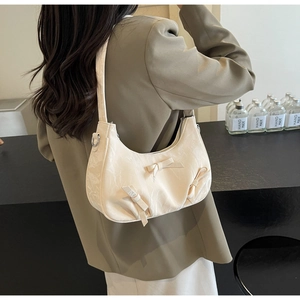 Detail of cream hobo bag with delicate bow accents and elegant pleated texture
