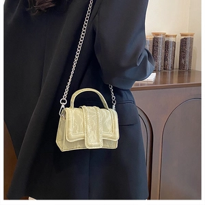 Detail of a mini cream handbag with marble texture and elegant silver chain strap
