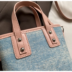 Detailed shot of rhinestone denim bucket bag with pink leather handle and silver rivets