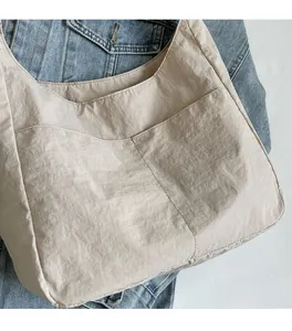 Textura detallada del bolso tote de nailon beige con tejido arrugado y bolsillo delantero