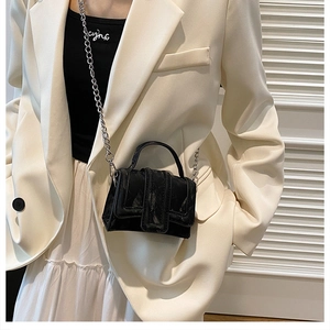 Close-up of mini black pleated handbag with silver chain and glossy cloud texture