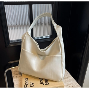 Détail du sac hobo blanc crème montrant le cuir texturé vertical et la poche frontale