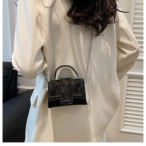 Mini black crossbody bag with embossed floral texture and silver chain strap shown on model