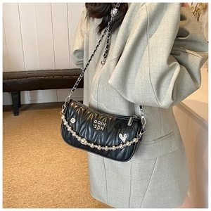 Detail of black V-quilted faux leather bag with elegant gold chain and heart charm