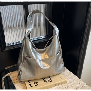 Grand sac Hobo argenté métallisé avec texture plissée posé sur un socle en marbre