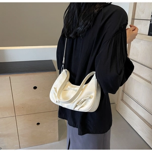 Close-up of off-white silk texture handbag with bow detail on a casual shoulder bag