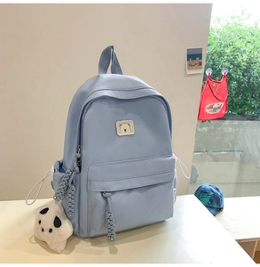 Close-up of light blue nylon backpack with front zipper pocket and cute white cat plush charm