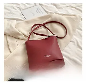 Detail of red bucket bag showing lychee grain leather texture and pearl chain strap