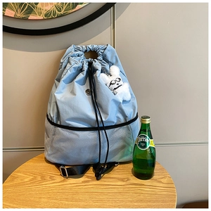 Detail eines hellblauen Nylon-Kordelzug-Rucksacks mit Netztasche und Plüschhasen-Anhänger
