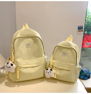 Detail of light yellow canvas backpacks in two sizes with cute bear patches and star charms