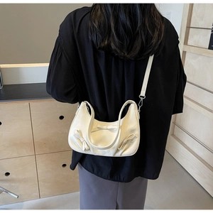 Detail of a creamy beige hobo bag featuring a decorative bow and versatile straps