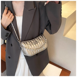 Close-up of silver quilted crossbody bag with metal chain strap and logo detail