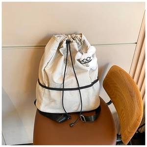 Detail eines beigen Nylon-Rucksacks mit Kordelzug, Netztasche und Plüschhund-Anhänger