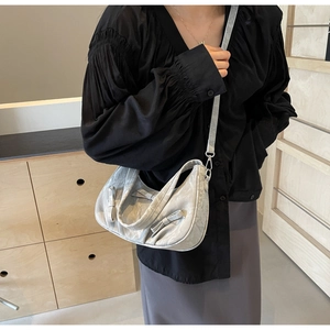 Detail of light grey hobo bag with bow accents and glossy wrinkled texture
