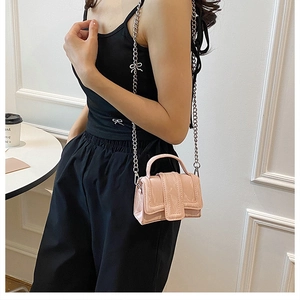 Close-up of bright pink patent leather mini crossbody bag with silver chain strap and handle