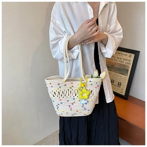 Détail du sac fourre-tout tissé avec pois colorés et breloque fleur jaune