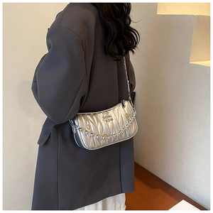 Detail of silver matelassé quilted chain bag with metallic bead strap worn by model