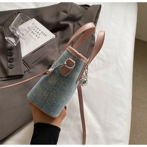 Detail showing blue denim bucket bag with pink leather trim and silver rivet accents