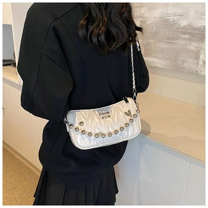 Detail of white quilted leather crossbody bag with silver chain and metal charm