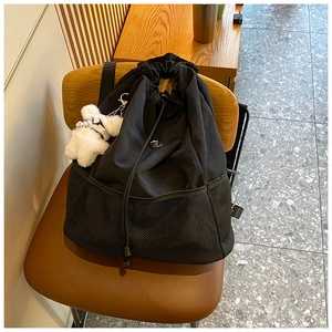 Detailansicht eines schwarzen Nylon-Rucksacks mit Netztasche und süßem Bärenanhänger