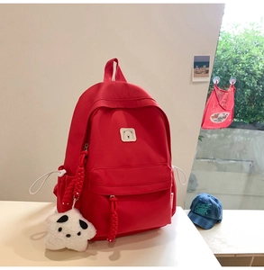Close-up of red canvas backpack with white star plush charm and side water bottle pocket