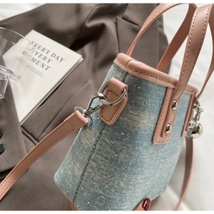 Detail of denim bucket bag with pink leather trim and decorative silver studs
