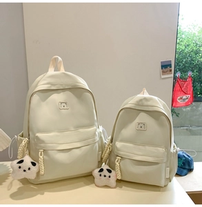 Close-up of minimalist off-white backpack details featuring bear embroidery and star plush