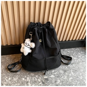 Detail eines schwarzen Nylon-Rucksacks mit Kordelzug, Netztasche und Hundeanhänger