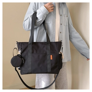 Detail of black nylon tote bag with wide strap and detachable round coin purse