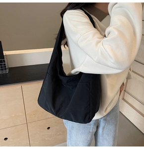 Vista detallada del bolso tote de nailon negro con textura plisada y correa de hombro