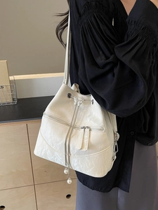 Beige bucket bag with drawstring, pearl charms and butterfly detail on model