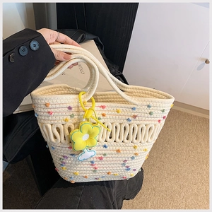 Détail du sac cabas tissé à la main avec points colorés et pendentif fleur jaune