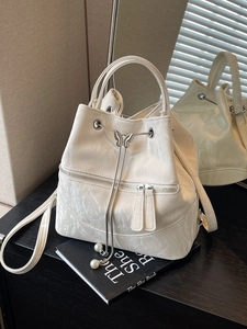 Creamy white bucket backpack with butterfly buckle and pearl charms on black book