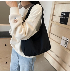 Bolso hobo grande de lona negra en modelo, con caída suave y diseño sencillo minimalista
