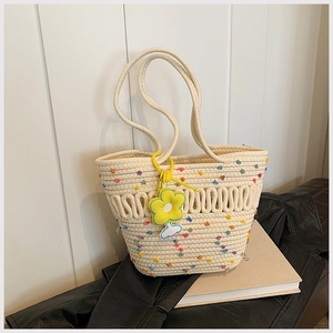 Détail du sac cabas tissé avec pois colorés et breloque tournesol jaune sur fond blanc