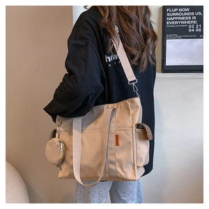 Detail view of large canvas tote bag with side logo tag and small round coin purse